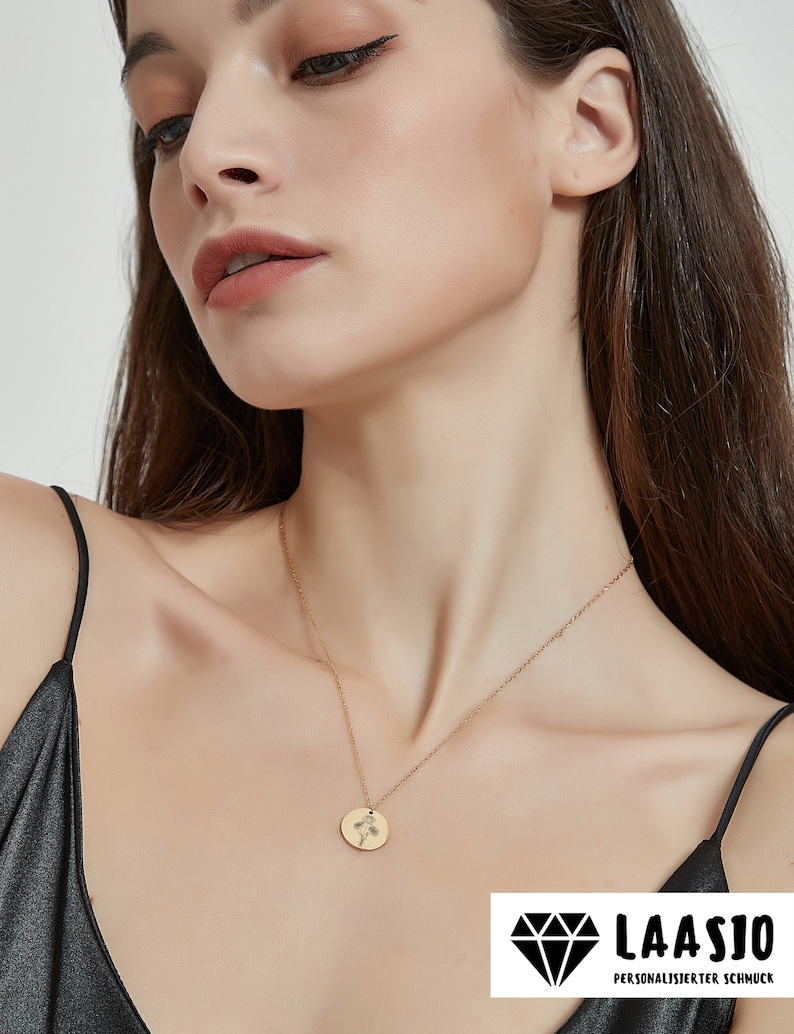 Peut inclure: Un collier dor&eacute; compos&eacute; d'une fine cha&icirc;ne et d'un petit pendentif circulaire. Le pendentif est grav&eacute; d'un motif floral d&eacute;licat aux lignes fines. Le collier repose sur le cou, mettant en valeur une finition m&eacute;tallique simple et polie.