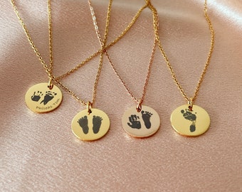 May include: Four gold necklaces with round pendants featuring imprinted baby footprints. One pendant has the names "Phineas Tom" engraved on it.