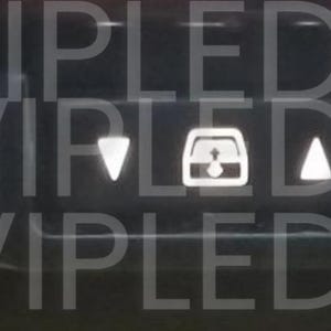 May include: Close-up of a car dashboard with illuminated symbols and text. The image features a defroster icon, power and normal settings, and the word "ECT". Additional text includes "Security" and "Passenger".