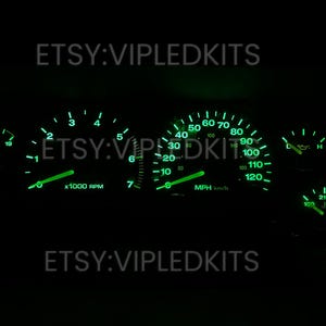 May include: A car dashboard with illuminated green gauges and dials against a black background. The speedometer reads up to 120 MPH. The image includes the text "ETSY:VIPLEDKITS".