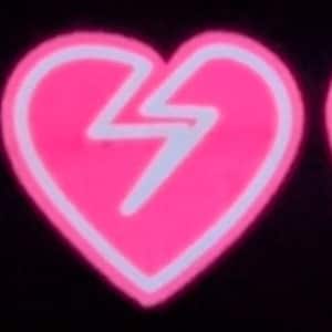 May include: Three pink heart-shaped patches with a white outline and a white lightning bolt inside each heart. The hearts are cracked down the middle.