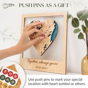 Puede incluir: Un mapa en forma de coraz&oacute;n de madera con un fondo turquesa, enmarcado en madera clara. El texto "Together, always yours" y la fecha "6/15/2023" est&aacute;n grabados en el marco. La imagen incluye chinchetas y el texto "PUSH PINS AS A GIFT".