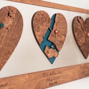 Puede incluir: Arte de mapa en forma de coraz&oacute;n de madera con un fondo azul turquesa. El mapa est&aacute; cortado con l&aacute;ser con detalles intrincados. El texto "We fell in love May 2023 Niagara Falls" est&aacute; grabado en el marco de madera. Una pieza &uacute;nica.