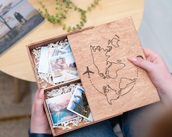 May include: A wooden box with a world map design and a small airplane graphic. The box is open and filled with small photos. The box is perfect for storing travel memories.