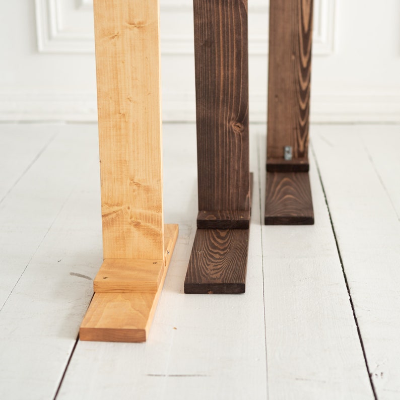 May include: Three wooden stands, one natural wood color and two stained dark brown, with a white background.