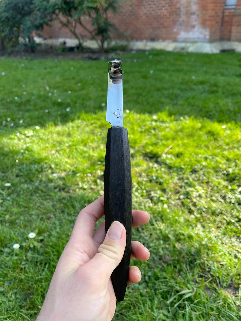 May include: A black handled paring knife with a silver blade. The blade has a small triangle logo on it.