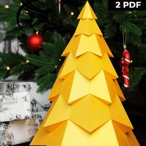 Puede incluir: Un árbol de Navidad de papel amarillo con un diseño geométrico. El árbol está decorado con un adorno de bastón de caramelo rojo. La imagen también incluye el texto: SVG, DXF, 2 PDF.