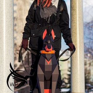 Peut inclure: Une femme portant un manteau d'hiver noir, un bonnet noir en tricot avec un pompon et une &eacute;charpe grise prom&egrave;ne un Doberman Pinscher en papier noir et rouge.
