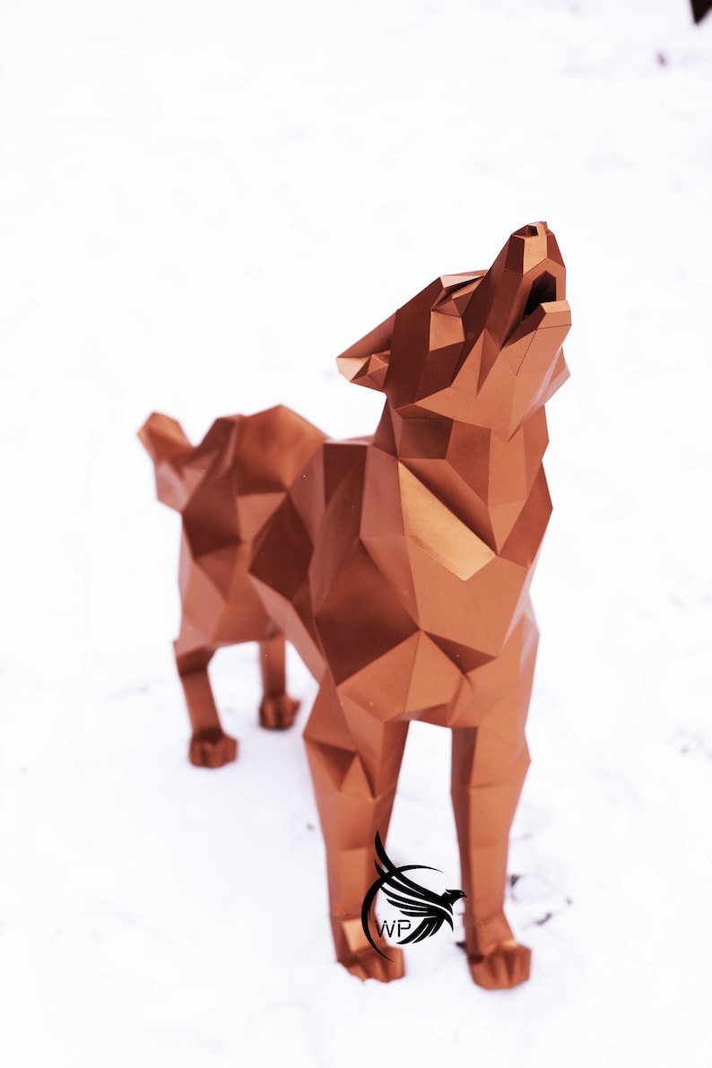 Puede incluir: Una escultura de lobo geom&eacute;trico de color cobre con un dise&ntilde;o estilizado. El lobo est&aacute; de pie sobre una superficie blanca y est&aacute; aullando con la cabeza echada hacia atr&aacute;s.
