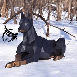 以下が含まれることがあります： 雪の中で横たわる犬の黒と金の幾何学的な彫刻。彫刻は多くの小さな三角形でできており、リアルな外観をしています。