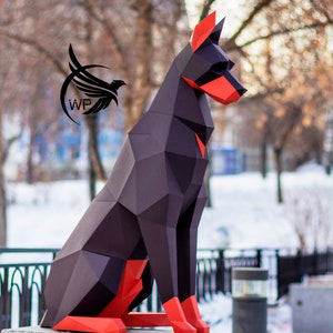 Peut inclure: Un mod&egrave;le de chien en origami en papier noir et rouge assis sur un pi&eacute;destal en pierre grise. Le chien est fait de papier pli&eacute; et a un design g&eacute;om&eacute;trique.