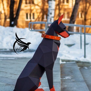 Peut inclure: Un chien origami Doberman Pinscher noir et orange assis sur un escalier en b&eacute;ton. Le chien porte un collier en cuir marron avec des clous argent&eacute;s.