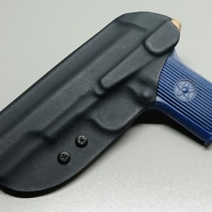 May include: A black leather holster with two screws on the bottom. A blue pistol with a star on the side is partially inside the holster.