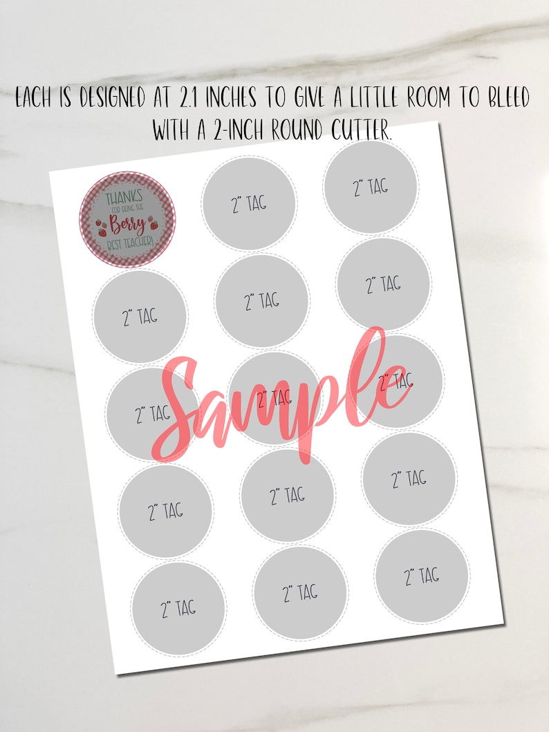 May include: A white sheet with gray circles labeled "2" TAC" and a pink "Sample" overlay. The top of the sheet has text that reads "EACH IS DESIGNED AT 2.1 INCHES TO GIVE A LITTLE ROOM TO BLEED WITH A 2-INCH ROUND CUTTER."