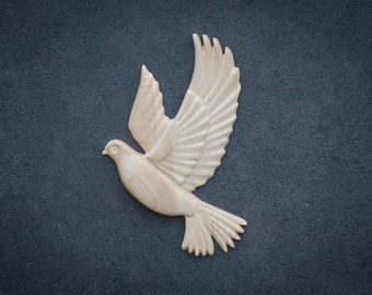 May include: A white wooden dove sculpture with its wings spread out in flight. The dove is carved in detail and has a realistic appearance.