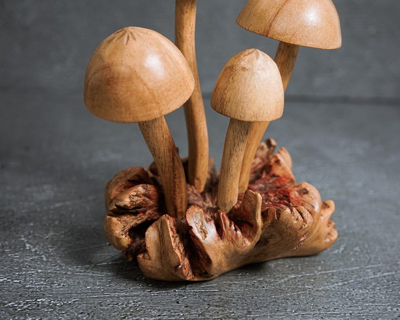 Pu&ograve; includere: Una scultura decorativa composta da quattro funghi in legno intagliato di diverse altezze, fissati su una base in legno naturale testurizzato. I funghi presentano cappelli lisci e arrotondati e steli sottili, con una venatura color legno chiaro.