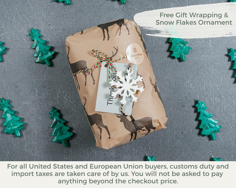 Pu&ograve; includere: Un regalo rettangolare avvolto in carta marrone con un motivo di cervi marrone scuro. Il pacchetto &egrave; legato con uno spago rosso, bianco e verde, decorato con un ornamento a forma di fiocco di neve bianco e un cartellino grigio chiaro con il testo Thank you.
