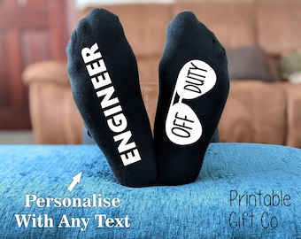 May include: A pair of black socks with white text. One sock says "Engineer" and the other says "Off Duty" with a pair of sunglasses graphic.