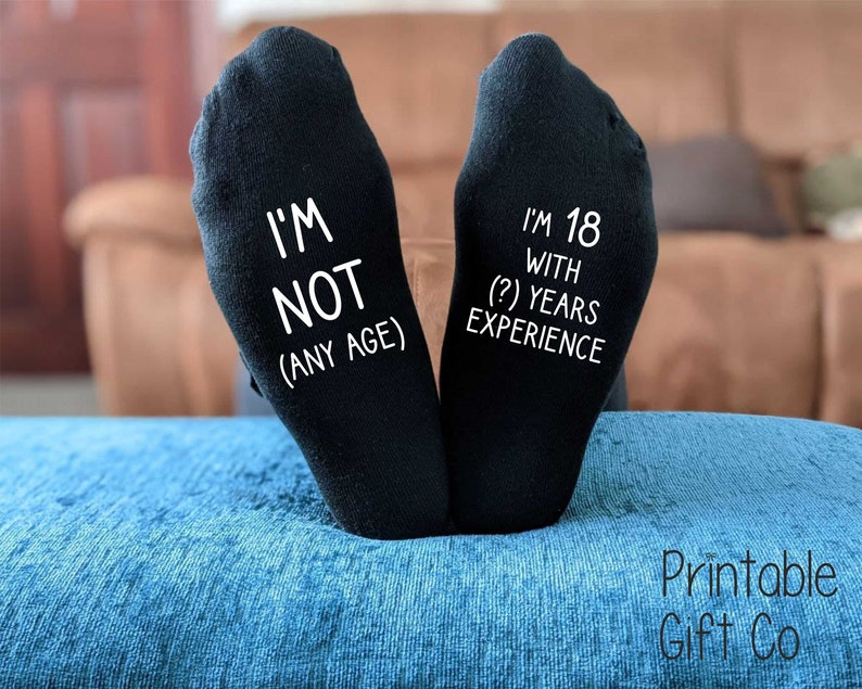 May include: A pair of black socks with white text. One sock says "I'm not (any age)" and the other says "I'm 18 with (?) years experience".