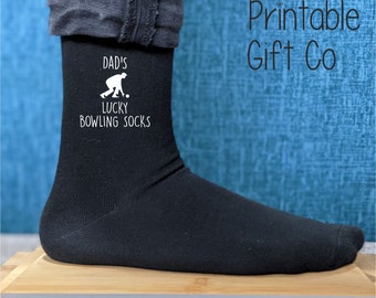 May include: Black socks with a white design that says "Dad's Lucky Bowling Socks" and a silhouette of a person bowling.
