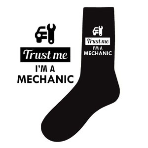 Puede incluir: Calcetines negros y blancos con un gráfico de un coche y una llave inglesa y el texto "Confía en mí, soy mecánico".