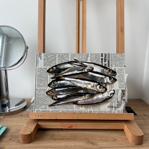 May include: A painting of a group of silver fish on a newspaper background. The newspaper headline reads "Zlodb-31 NE MO" and the artist's signature is visible in the bottom right corner.