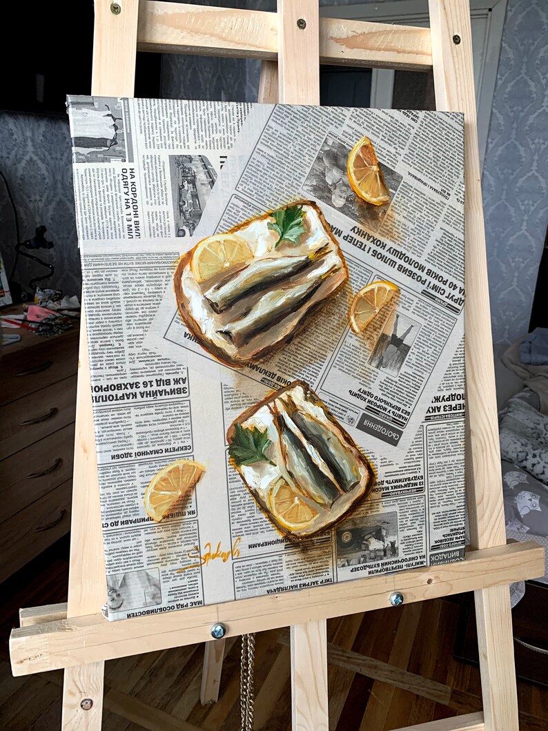 May include: A painting of two open-faced sandwiches with sardines, lemon slices, and parsley on a newspaper background.
