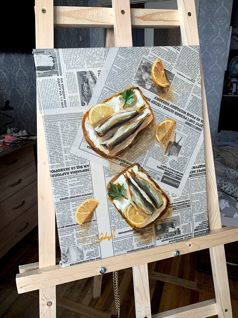 May include: A painting of two open-faced sandwiches with sardines, lemon slices, and parsley on a newspaper background.