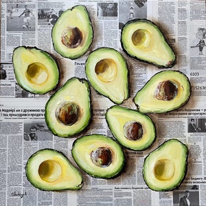 May include: A still life painting of 10 avocados on a newspaper background. The avocados are painted in a realistic style with green skin and brown pits. The newspaper is printed in a variety of languages.