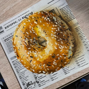 May include: A close-up of a painted bagel with a white center and a yellow outer ring. The bagel is covered in white and black sesame seeds.