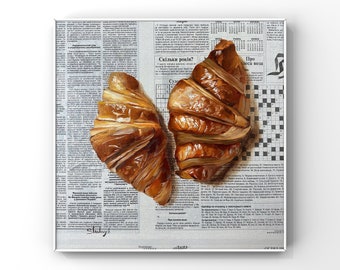 May include: Two golden brown croissants on a newspaper background. The newspaper has text in Ukrainian, including the words "Скільки років?" which translates to "How many years?"