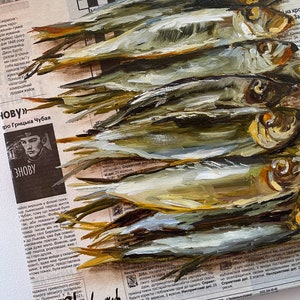 May include: A painting of a group of silver fish on a newspaper background. The fish are painted in a realistic style with details of scales and fins. The newspaper background is partially visible and includes text and a crossword puzzle.