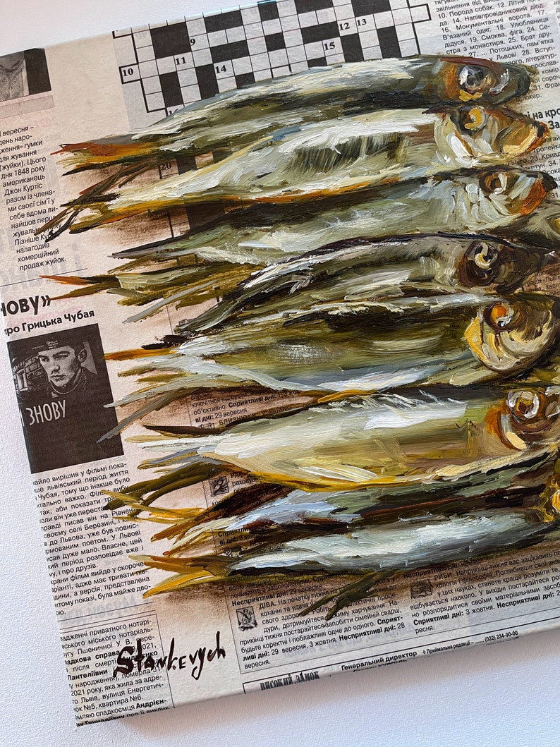 May include: A painting of a group of silver fish on a newspaper background. The fish are painted in a realistic style with details of scales and fins. The newspaper background is partially visible and includes text and a crossword puzzle.