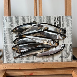 May include: A painting of a group of silver fish on a newspaper background. The newspaper headline reads "Сила віри" and "Злодь ЗЦ НЕ МОГЛ".