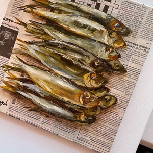 May include: A painting of a pile of dried fish on a newspaper background. The fish are arranged in a vertical stack, with the tails at the top and the heads at the bottom. The fish are a light brown color with a slightly iridescent sheen. The newspaper is a light brown color with black text.