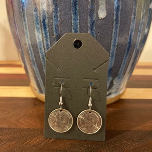 May include: A pair of silver earrings featuring a dime coin design. The dimes are dated 2022 and have the profile of a person on them.