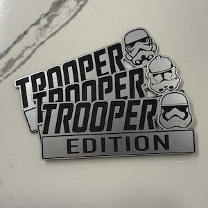 May include: A set of three ceramic mugs with a speckled, matte finish. The mugs are in shades of cream, light gray, and dark gray. Each mug has a simple, minimalist design, perfect for coffee or tea.