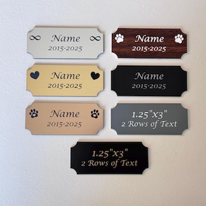 May include: Six different styles of personalized pet ID tags. The tags are made of metal and have a variety of finishes, including silver, gold, black, and brown. The tags are engraved with the text "Name 2015-2025" and feature different designs, including paw prints, hearts, and infinity symbols. Some tags also include the text "1.25" x 3" 2 Rows of Text".