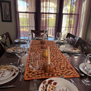 Peut inclure: Une table de salle &agrave; manger dress&eacute;e pour un repas, avec des assiettes portant le mot "Grateful" et des motifs de feuilles d'automne. Un chemin de table sur le th&egrave;me de la citrouille, des citrouilles d&eacute;coratives et des bougies sont pr&eacute;sents.