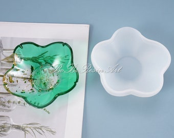 Puede incluir: Un molde de silicona transparente con forma de estrella de cinco puntas, con una fundición de resina verde de la misma forma en el fondo.