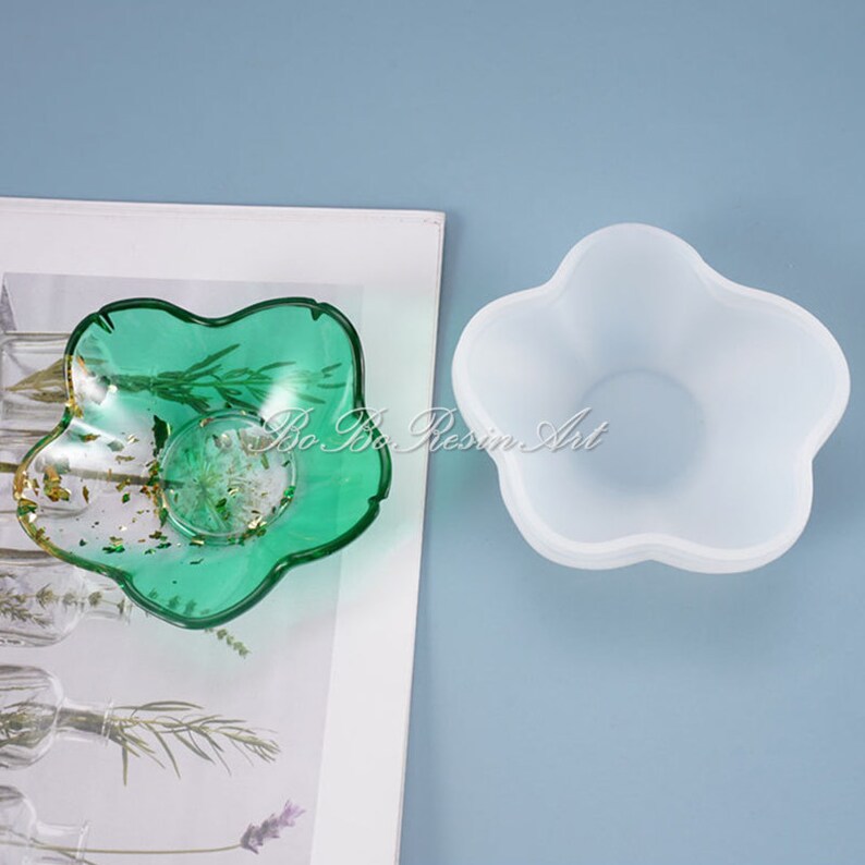 May include: A clear silicone mold shaped like a five-pointed star, with a green resin casting of the same shape in the background.