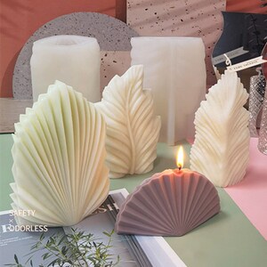 Può includere: Un set di cinque stampi per candele in varie forme, tra cui un ventaglio, una foglia e una conchiglia. Gli stampi sono in silicone bianco e sono pronti per essere utilizzati per creare candele.