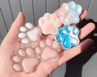 Può includere: Sei ciondoli a forma di zampa di animale in resina di vari colori, tra cui rosa, bianco e blu. I ciondoli hanno una finitura scintillante e sono perfetti per la creazione di gioielli o per l'artigianato.