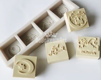 Puede incluir: Un molde de silicona con cuatro diseños diferentes para hacer manualidades de resina. Los diseños incluyen una luna creciente y una estrella, una mezquita con una luna creciente, las palabras "Eid Mubarak" en escritura árabe y las palabras "Eid Mubarak" en escritura inglesa.