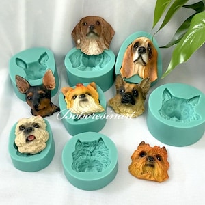 Può includere: Nove stampi in silicone per realizzare forme di testa di cane. Gli stampi sono di colore verde acqua e ogni stampo rappresenta una razza di cane diversa. Le teste di cane sono realizzate in materiale marrone, bianco e nero.