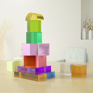May include: A stack of colorful acrylic blocks in various shapes and sizes. The blocks are arranged in a tower, with the largest block at the bottom and the smallest block at the top. The blocks are made of clear acrylic and have a variety of colors, including green, purple, pink, orange, and yellow.