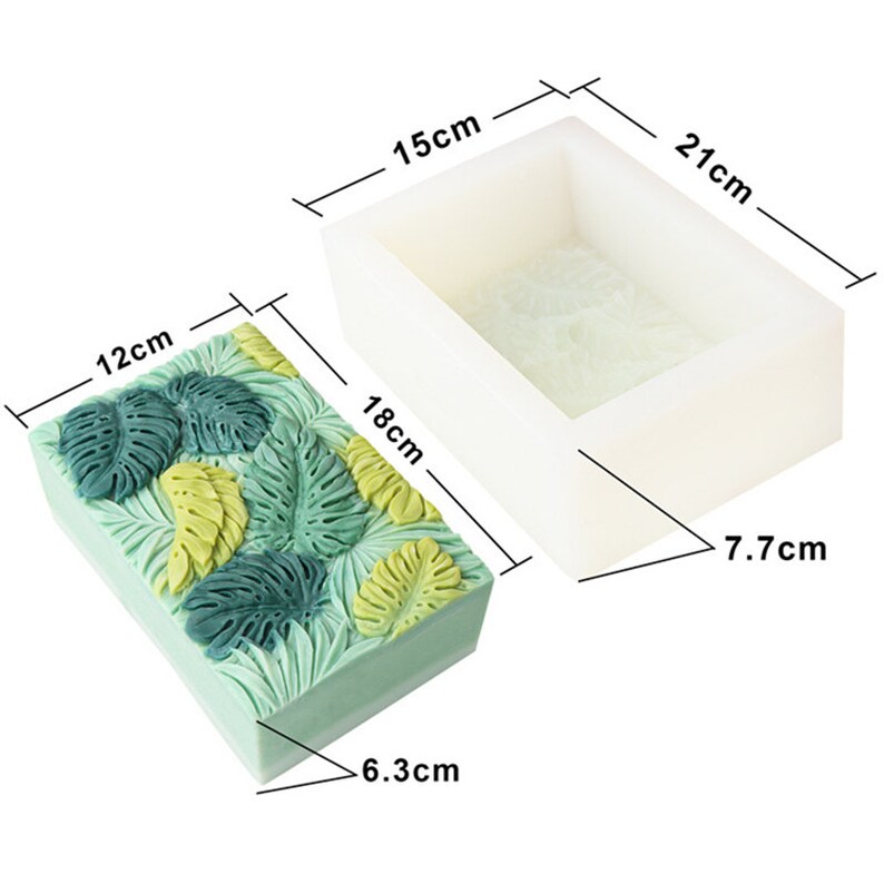 May include: A rectangular soap mold and a finished soap bar. The soap bar is light green with a raised leaf design in shades of green and yellow. The mold is white and rectangular, measuring 21 cm x 15 cm x 7.7 cm.