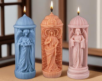 May include: Three pillar candles with religious figures carved into them. The candles are in shades of blue, peach, and pink. Each candle has a flame burning at the top. The candles are in a row, with the figures facing forward.