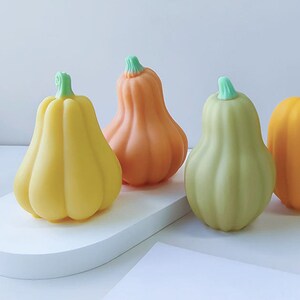 Peut inclure: Quatre citrouilles d&eacute;coratives en jaune, orange et vert. Les citrouilles ont la forme de citrouilles et une finition lisse et brillante.