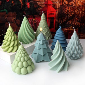 Puede incluir: Un conjunto de ocho velas de árbol de Navidad verdes y azules. Las velas son de diferentes formas y tamaños, y algunas tienen una superficie texturizada.